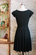 Knee length black pleated dress with cap sleeves in triacetate back view