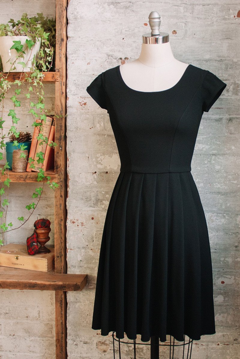 Knee length black pleated dress with cap sleeves in triacetate